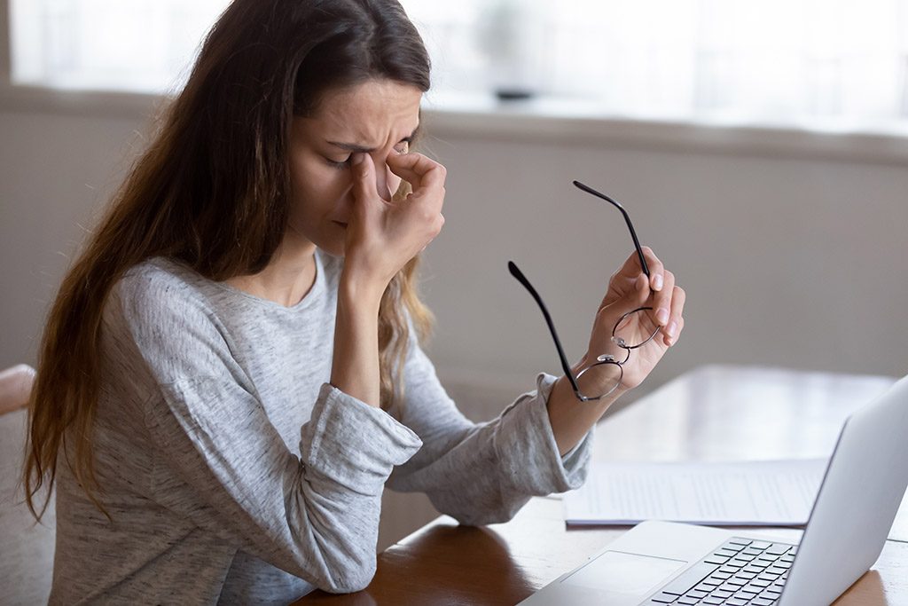 Head shot exhausted young woman taking off glasses, suffer from eyes strain due to computer overwork. Tired unhealthy millennial mixed race lady having painful feelings, blurred vision syndrome.